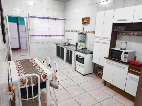 a kitchen with white cabinets and a table in it at Casa Maria Vitória in Aparecida