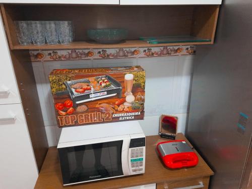 a microwave on a table with a box on top of it at Casa Maria Vitória in Aparecida
