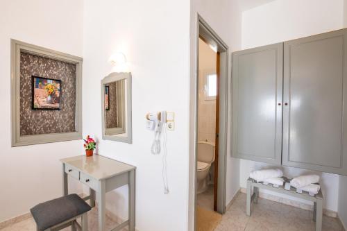 a bathroom with a toilet and a table and a cabinet at Perama Hotel, Karpathos in Amoopi