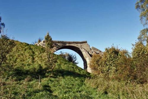 a bridge on a grassy hill with a blue sky at W sercu Mazur in Kruklanki