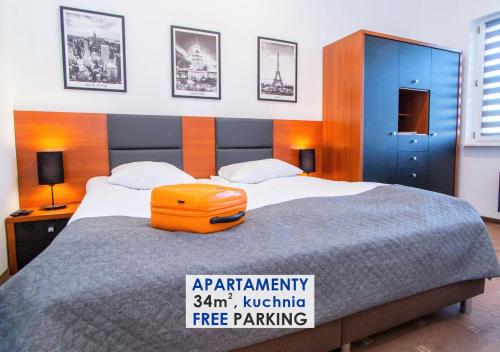 Un dormitorio con una cama con una maleta naranja. en Warsaw Apartments - Apartamenty Sadyba, en Varsovia