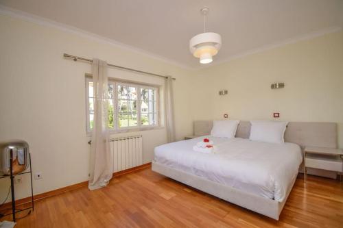 ein Schlafzimmer mit einem weißen Bett und einem Fenster in der Unterkunft Luxurious 4-bedroom golf villa with private pool in Sintra