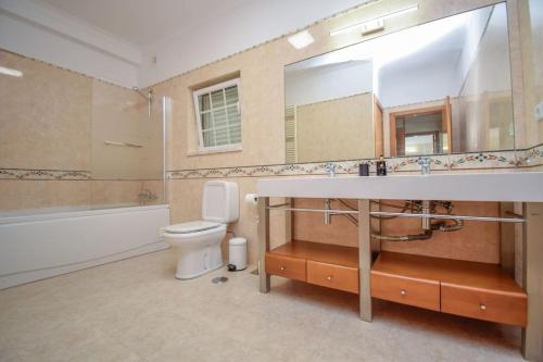 La salle de bains est pourvue d'un lavabo, de toilettes et d'un miroir. dans l'établissement Luxurious 4-bedroom golf villa with private pool, à Sintra