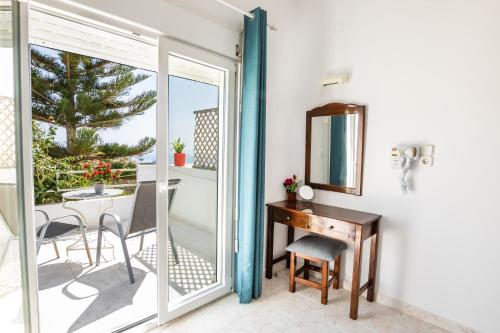 a room with a desk and a balcony with a table and chairs at Perama Hotel, Karpathos in Amoopi