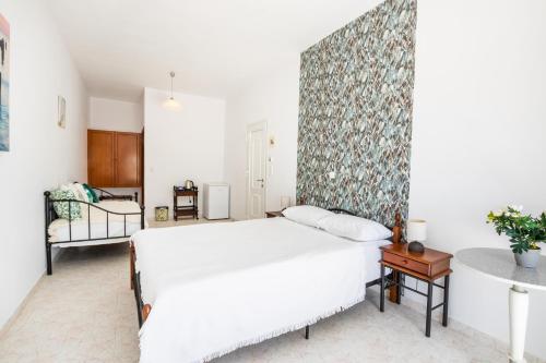 a bedroom with a white bed and a wall at Perama Hotel, Karpathos in Amoopi