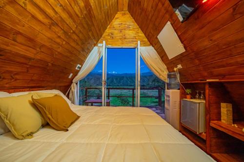 a bedroom with a large bed with a large window at GLAMPING CACHI EL PARAISO DE NALA in Cachí