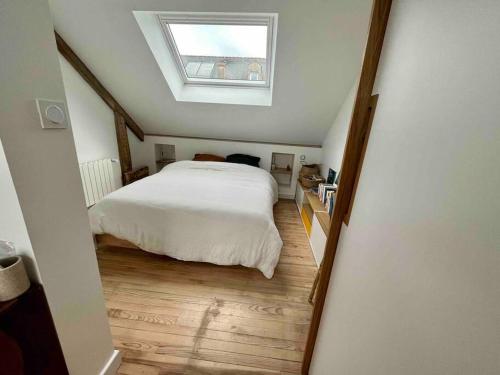 une chambre avec un lit blanc et une lucarne dans l'établissement Maison familiale au calme, à Lorient