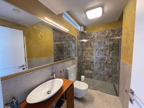 a bathroom with a sink and a toilet at Deluxe Sunrise Sky Terrasse 2 Bedroom Design Apartment & Fantastic Lake View in Maderno