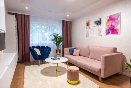 a living room with a pink couch and blue chairs at Poetic Apartment Vaslui in Vaslui