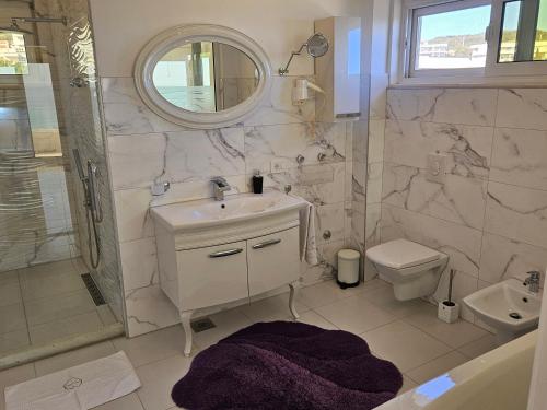ein Badezimmer mit einem Waschbecken, einem WC und einem Spiegel in der Unterkunft Apartments D'Hermes in Ulcinj