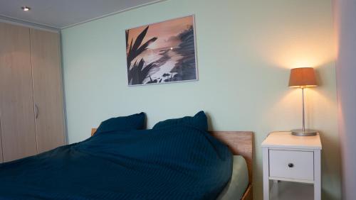 a bedroom with a blue bed and a nightstand with a lamp at Wad'N Huis in Westerland