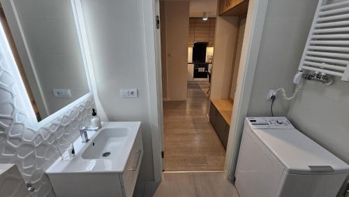 a white bathroom with a sink and a mirror at Apartament Faleza in Rewal