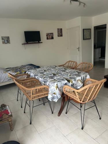a table with chairs and a bed in a room at Les Gîtes de la Colo in Ravenoville