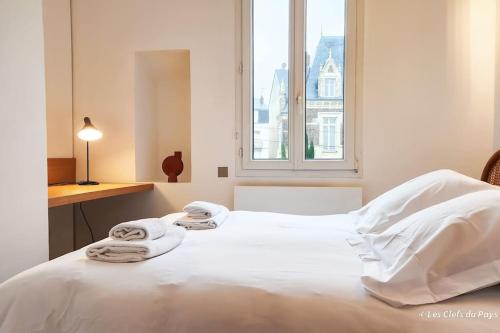 Un dormitorio con una cama blanca con toallas. en Superbe maison de standing-plein cœur de Deauville, en Deauville