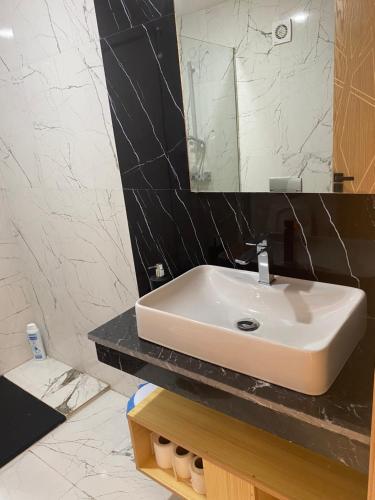 La salle de bains est pourvue d'un lavabo blanc et d'un miroir. dans l'établissement Le Confort Proche de l'Aéroport, à Nouaceur