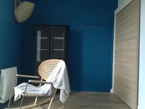 une chaise dans une pièce avec un mur bleu dans l'établissement Appartement vue sur mer, à Erquy