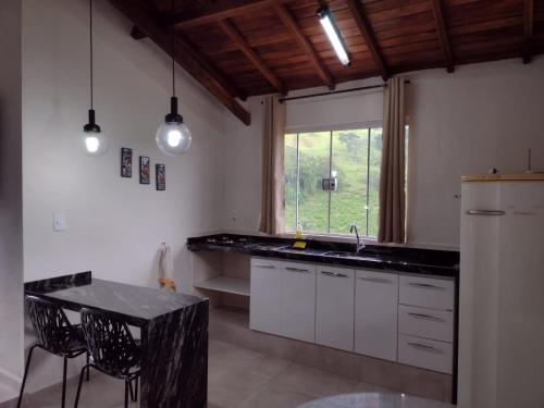 ブエノ・ブランダンにあるChalés Recanto das Floresのキッチン(シンク、テーブル付)、窓が備わります。