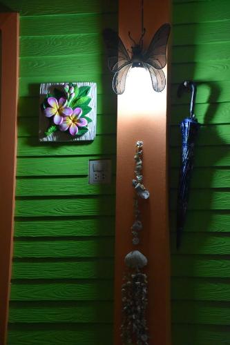 a butterfly on a green wall next to a light at Kama Siri Koh Kood in Ko Kood