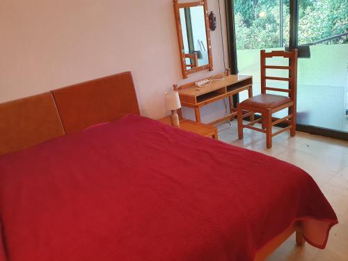 um quarto com uma cama vermelha, uma secretária e uma cadeira em ΔΕΛΦΊΝΙΑ em Néa Palátia
