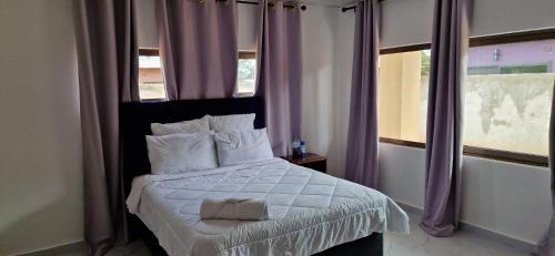 a bedroom with a large bed with purple curtains at Shalom Apartments Kalumbila in Musele