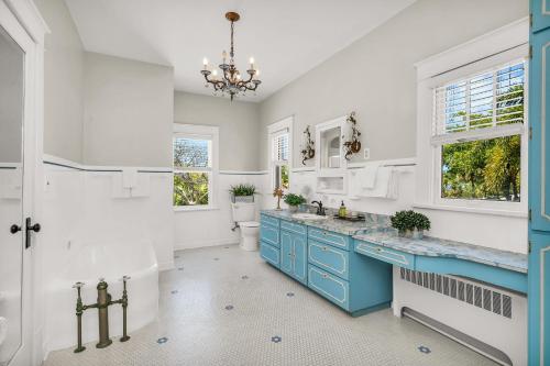 a bathroom with blue cabinets and a toilet and a chandelier at Birds of Paradise: Unwind in Nature's Embrace in Lantana