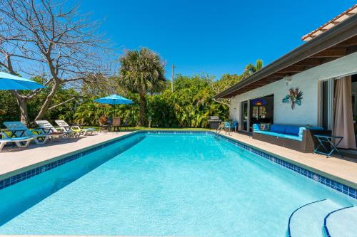 a swimming pool with chairs and umbrellas next to a house at Birds of Paradise: Unwind in Nature's Embrace in Lantana