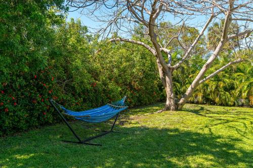 a blue hammock sitting in the grass next to a tree at Birds of Paradise: Unwind in Nature's Embrace in Lantana