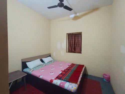 Schlafzimmer mit einem Bett und einem Deckenventilator in der Unterkunft Green cottage in Gokarna