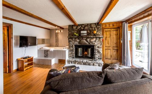 a living room with a couch and a stone fireplace at Chalets Lac à la Truite in Sainte-Agathe-des-Monts