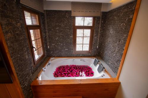 a bath tub filled with pink flowers in a bathroom at Kervansaray Deluxe Hotel in Ayder Yaylasi