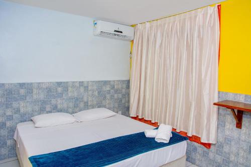 a bedroom with a bed and a window with towels at Pousada Flat Castor in Natal
