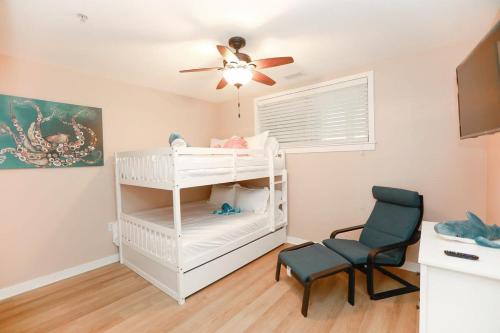 um quarto com um berço branco e uma cadeira em Sojourn Sanctuary Seaside Escape 3 BR em Virginia Beach