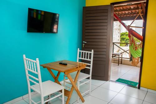 Pousada Flat Castor في ناتال: غرفة طعام مع طاولة وكراسي وتلفزيون