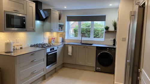a kitchen with a stove and a sink and a dishwasher at Whittaker Mews near Alton Towers JCB in Rocester