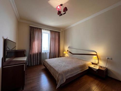 una camera da letto con un letto, una scrivania e una televisione di Sweet Home a Yerevan