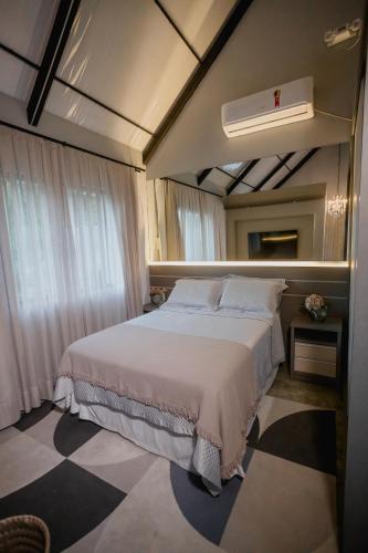 a bedroom with a large bed with a white comforter at Recanto Fogo na Taça (Chalé das Oliveiras) in Jaraguá do Sul