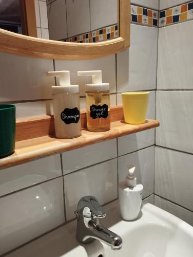 La salle de bains est pourvue d'un lavabo et de tasses sur une étagère. dans l'établissement 13-Beds with Sauna - Morzine - Easy walk to Centre, à Morzine