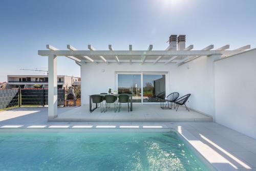 a patio with a table and chairs and a swimming pool at Kuća za odmor Finida in Umag