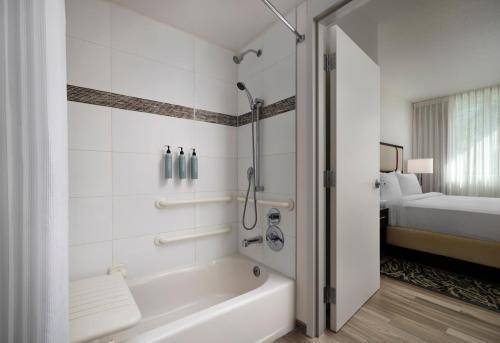 a bathroom with a tub and a shower with a bed at Residence Inn by Marriott Miami Beach Surfside in Miami Beach