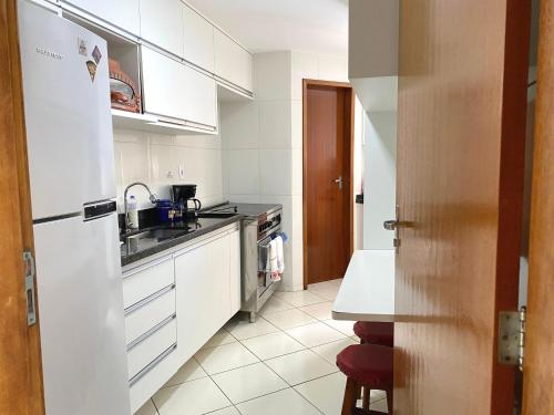 La cuisine blanche est équipée d'un évier et d'un réfrigérateur. dans l'établissement Beachfront apartment, à Vila Velha