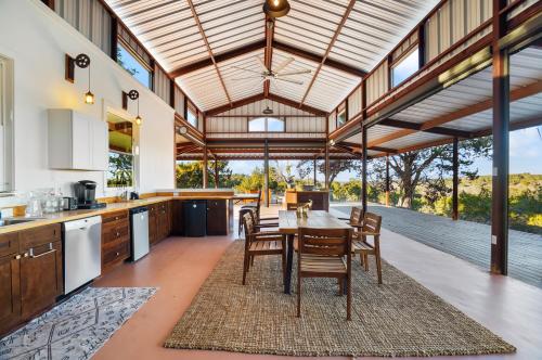 une cuisine ouverte et une salle à manger avec une table et des chaises dans l'établissement Hill Country Safari Tent and Recreational Pavilion and Cowboy Pool!, à Dripping Springs