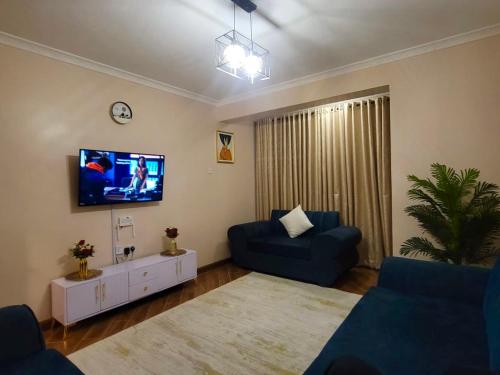 a living room with a blue couch and a tv at Vogue Homes in Nakuru