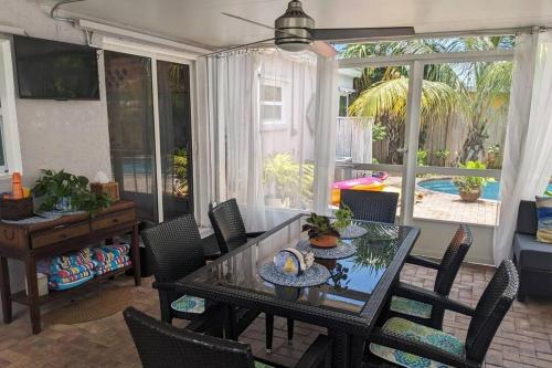 uma sala de jantar com uma mesa de vidro e cadeiras em The Ave House- Private Oasis Retreat W/heated Pool em Fort Lauderdale