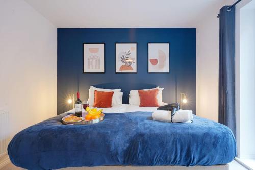 Una gran cama azul con una bandeja de comida. en Luxury Campbell Park Apartments in Central MK with Balcony, Free Parking & Smart TV with Netflix by Yoko Property, en Milton Keynes