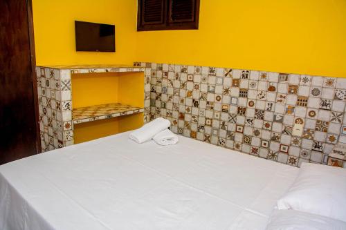 a room with a bed and a tiled wall at Pousada Flat Castor in Natal
