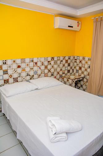 a bedroom with a white bed with towels on it at Pousada Flat Castor in Natal