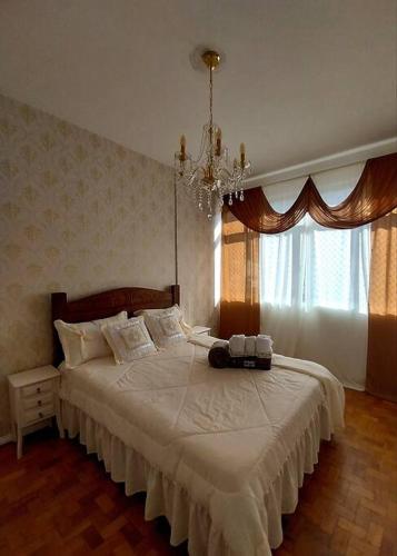 a bedroom with a large white bed with a chandelier at Apto 3 quartos, no Centro. Temático e acolhedor! in Nova Friburgo