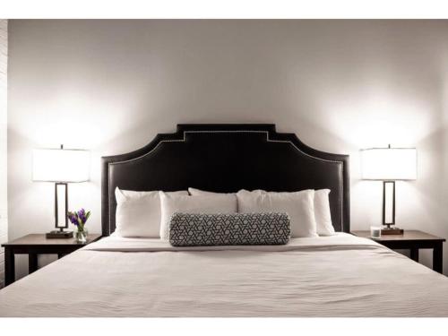1 cama con cabecero negro y 2 lámparas en BOLD 2BR 2BA In The Block Apartment by CozySuites!, en Indianápolis