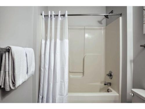 baño con ducha con cortina blanca en BOLD 2BR 2BA In The Block Apartment by CozySuites!, en Indianápolis