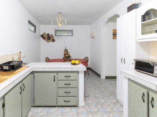 a kitchen with white cabinets and a counter with fruit on it at Villa Copthall in Roseau